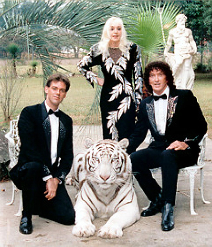 Three formally dressed people with a white tiger